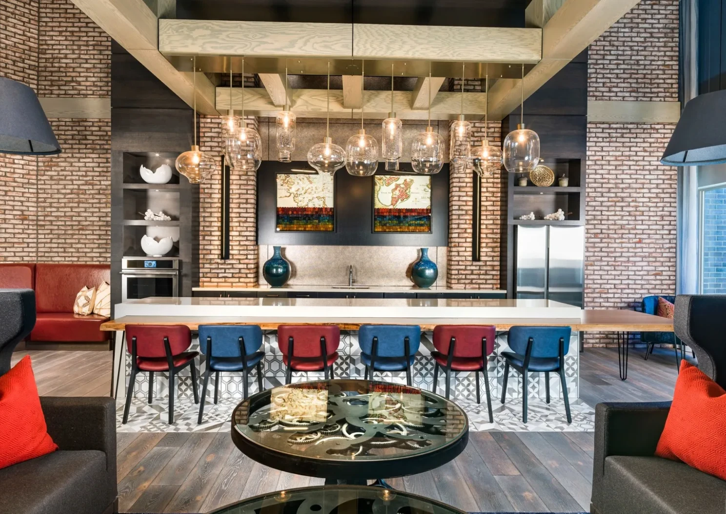 Stylish communal space with modern decor, red chairs, and industrial lighting over a countertop