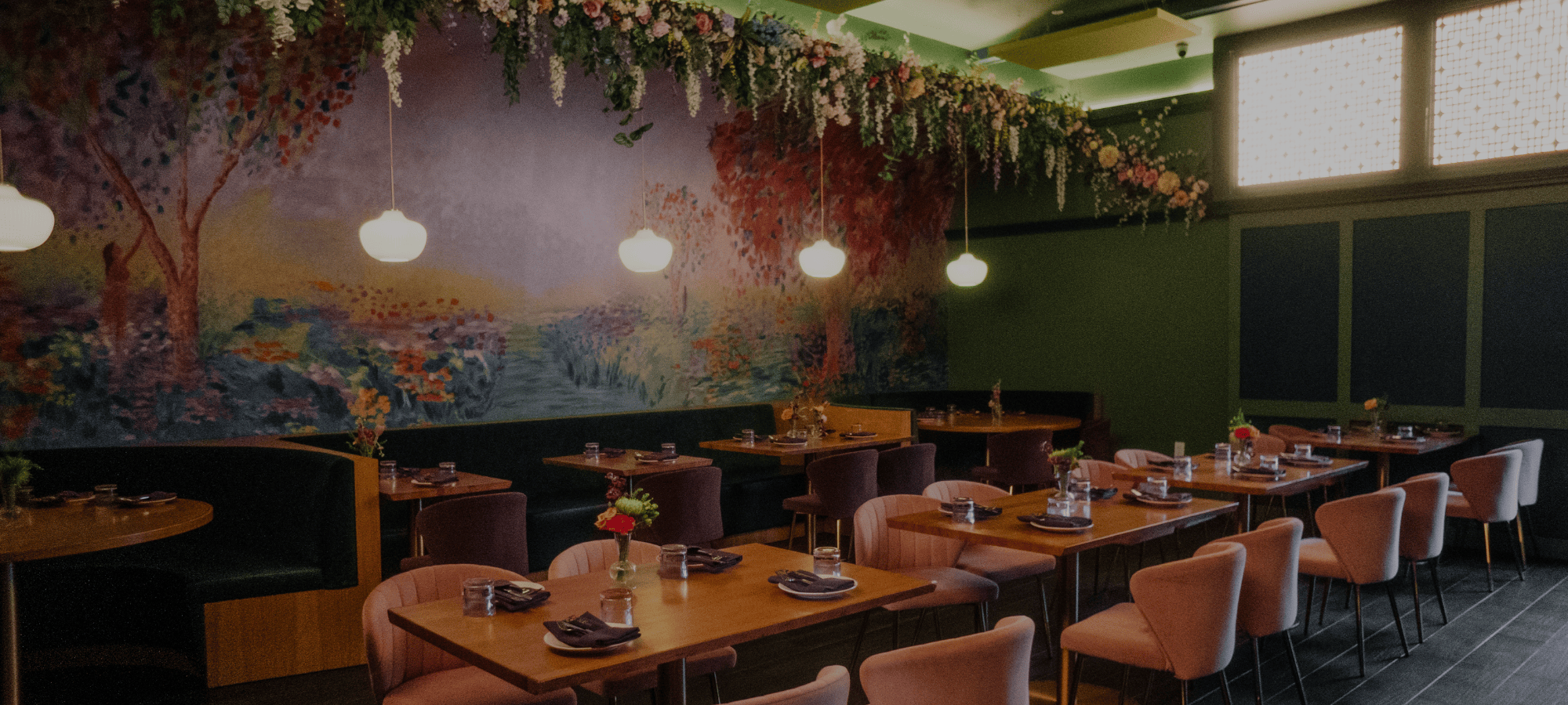 Image of Nue restaurant seating, showing off a bright mural and hanging flowers